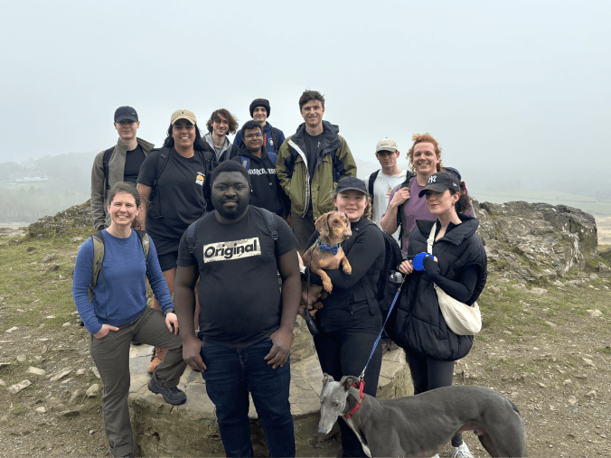 A photo of the research group and two dogs in front of a foggy landscape